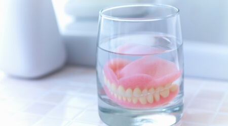 Full set of dentures in a glass of water