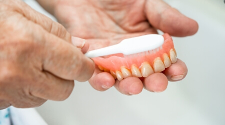 Person brushing denture