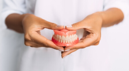 Person holding a full set of dentures