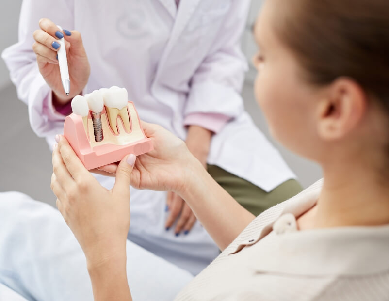 Dentist and patient looking at dental implant model