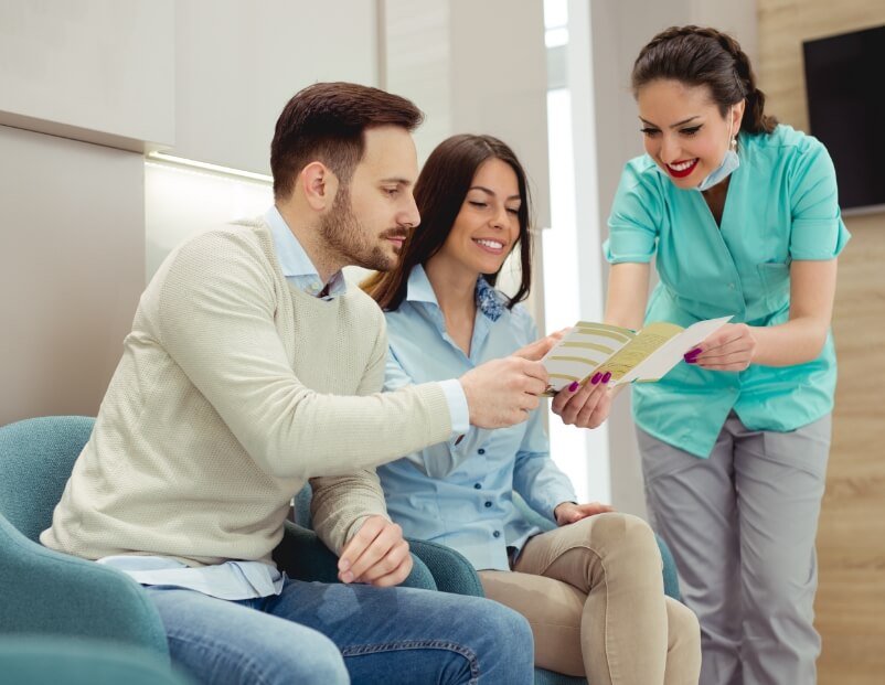 Dental team member talking with two patients