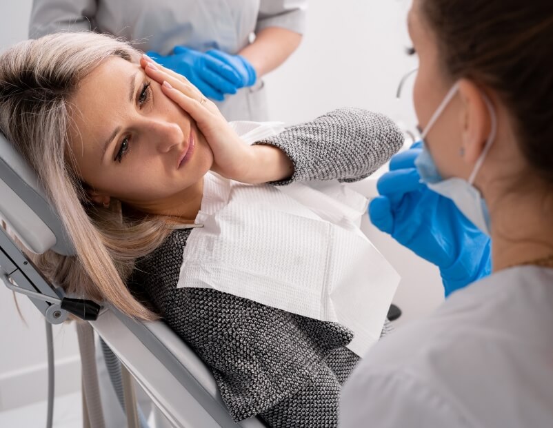Woman holding cheek before restorative dentistry