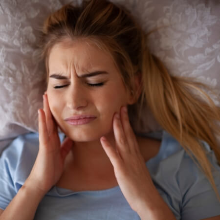 Woman holding jaw joints in pain