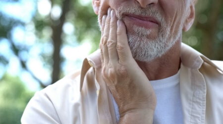 Older person with arthritis holding jaw