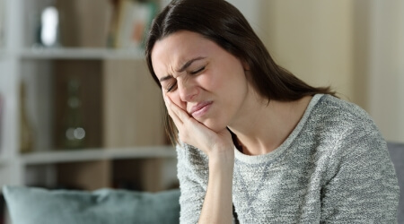 Woman with injury holding jaw in pain